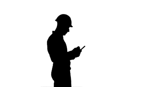 Silhouette Contractor Engineer in Hardhat Inspecting Construction Site Holding Digital Tablet
