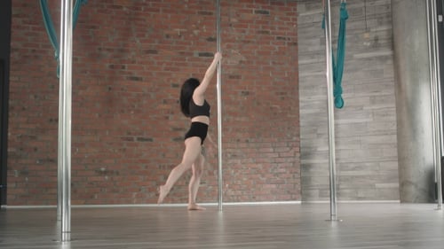 Young Woman Doing Pole Dancing Routine Indoors