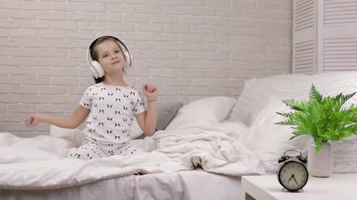 Young Girl Dancing in Headphones on Bed