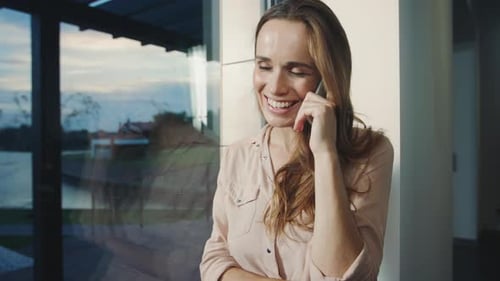 Smiling Woman Chatting on Phone by Window