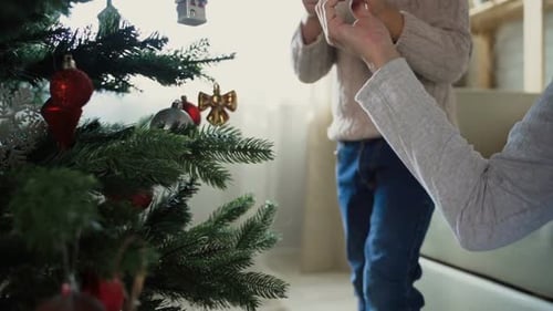 Child Decorating Christmas Tree with Parent