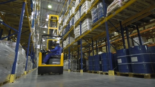 Warehouse Worker on Stacker Loading Cargo on Shelf