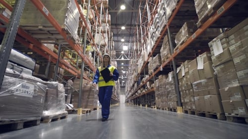 Un trabajador del almacén recorre las hileras del almacén