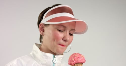 Mujer de estilo deportivo come helado y sonriendo