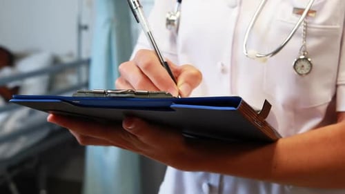 Medical Professional Writing on Clipboard in Hospital