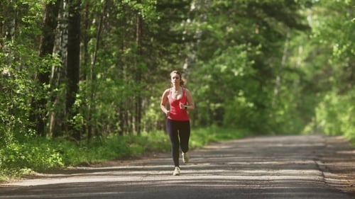 Young Woman Jogging in Summer Forest. the Girl Goes Sports in the Nature