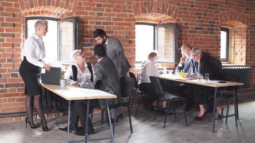 Old and Young Employees Involved in Teamwork in Workplace with Laptops
