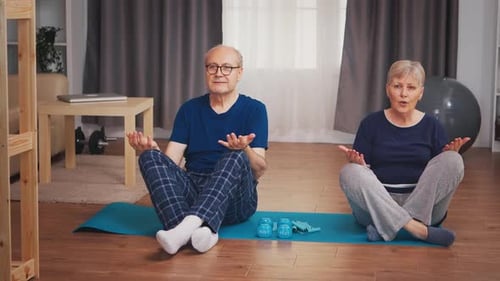 Senior Couple Meditating on Exercise Mat at Home