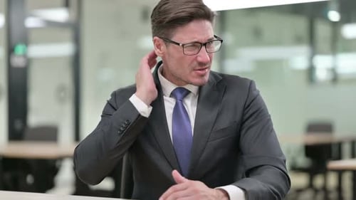 Mature Man Rubbing His Aching Neck at Work