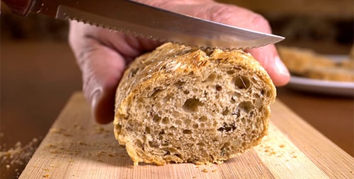 Slicing Fresh Bread on Cutting Board at Home