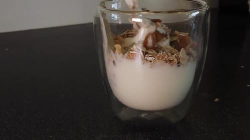 Granola and Yogurt Being Mixed in Glass