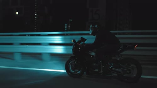 A Man Rides a Sports Motorcycle Through the City at Night