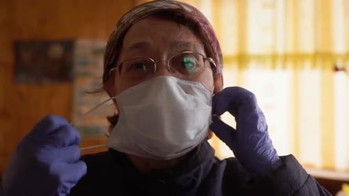 Woman Removing a Face Mask with Gloves On