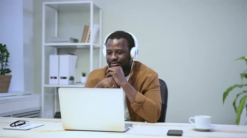 Smiling Man Using Laptop in Bright Workplace