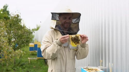 Closeup Portrait of Beekeeper Holding a Honeycomb Full of Bees