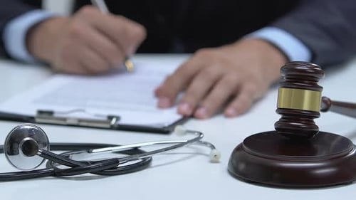 Stethoscope and Gavel with Paperwork and Lawyer Writing