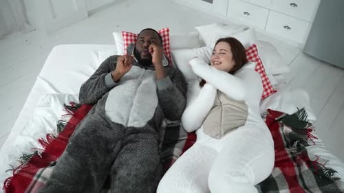 Couple Dances in Pajamas Lying on Bed Together