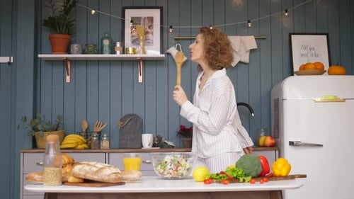 Woman Dances and Sings with Spoon in Kitchen