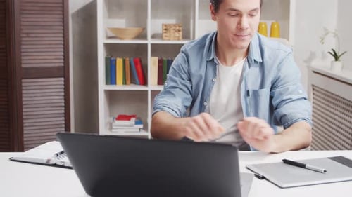 Workplace of freelance worker at home office. Young man works using computer.