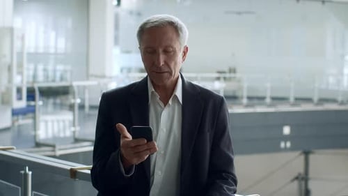 MiddleAged Businessman Texting On Phone Shaking Fists In Office Center