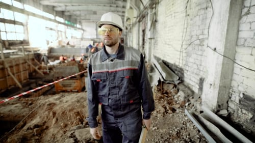 Construction Worker Walking Through Building Site