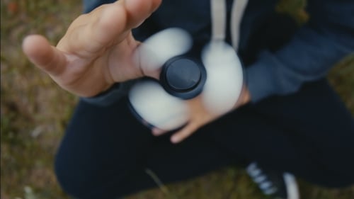 Person Holding and Spinning a Fidget Spinner