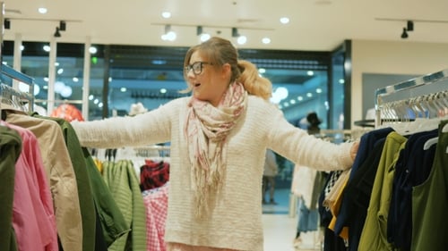 Verrücktes Mädchen beim Einkaufen im großen Einkaufszentrum, weibliche Shopaholic kauft Kleidung im Geschäft