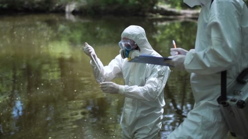 Scientists Sampling Water in Protective Suits by Lake