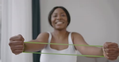 Woman Exercising with Green Resistance Band at Home