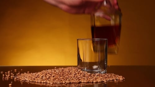 Whiskey Pour with Grains and Gold Background