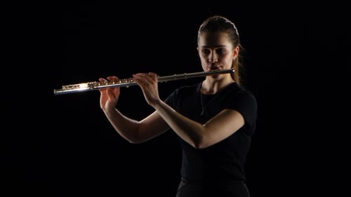Female Plays on the Flute Classical Melodies. Black Studio Background