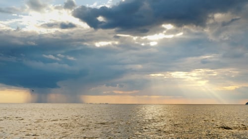 Strong Rain Far Into the Sea and the Setting Sun with Beautiful Rays