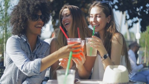 Cheerful Women Toasting Drinks at Outdoor Cafe