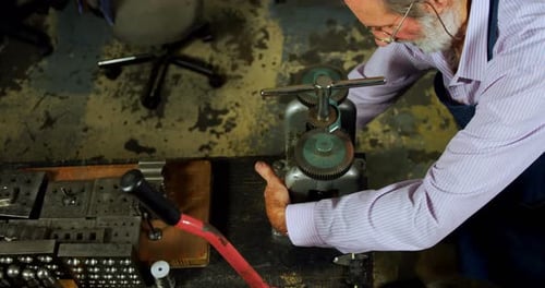 Goldsmith working on machine in workshop