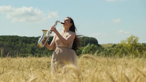 Beautiful Longhaired Brunette Woman Jazz Performer Plays Saxophone Outdoors in Field with Blue Sky