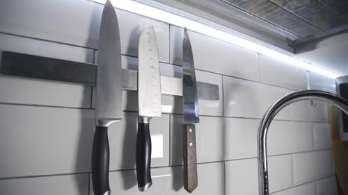 Hand Reaching For Knife on Kitchen Wall