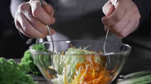 Der Koch macht Gemüsesalat mit Kohl und Karotten, vegetarisches Essen, frische Lebensmittel und Vitamine