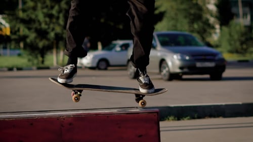 Shot of the Feet of an Adult Teenager Who Performs a Jump on a Big Fanbox in a Self-made Skatepark