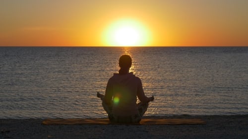 Woman in Lotus Pose at Sunset Near Sea