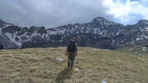 Backpacker Hiking Toward Snowy Mountain Range