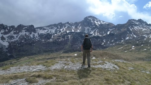 Le randonneur monte au sommet et lève les bras dans le geste de la victoire