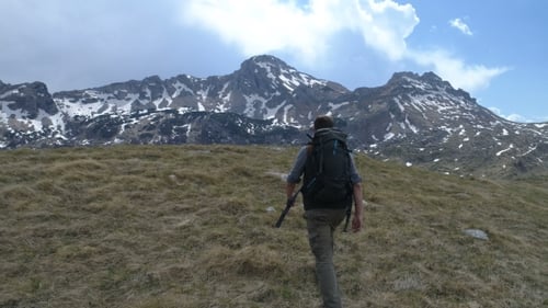 Le randonneur monte au sommet et lève les bras dans le geste de la victoire