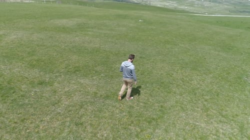 Man Is Walking Along the Grassy Field