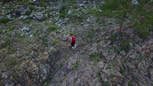 Girl Tourist with a Backpack Sneaking Through the Rocky Terrain