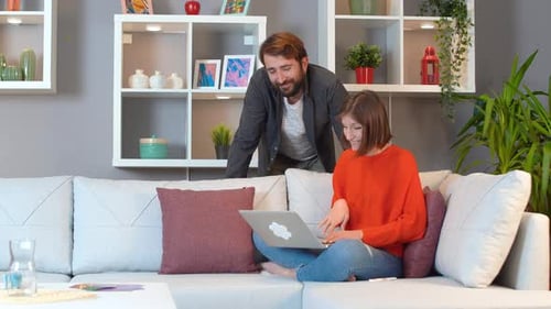 Woman Works on Laptop with Man Watching Over