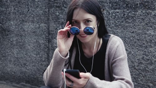 Woman Listening to Music and Using Smartphone in City