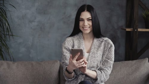 Woman Interacts with Smartphone in Cozy Setting