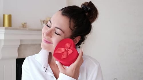 Woman Smiles Holding Red Heart Shaped Gift Box