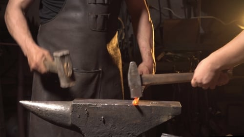 Craftsman Forging Hot Metal on Anvil in Workshop