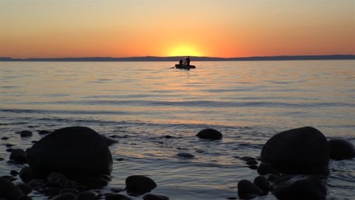 Tranquil Sunset Over Ocean with Rowboat Silhouettes